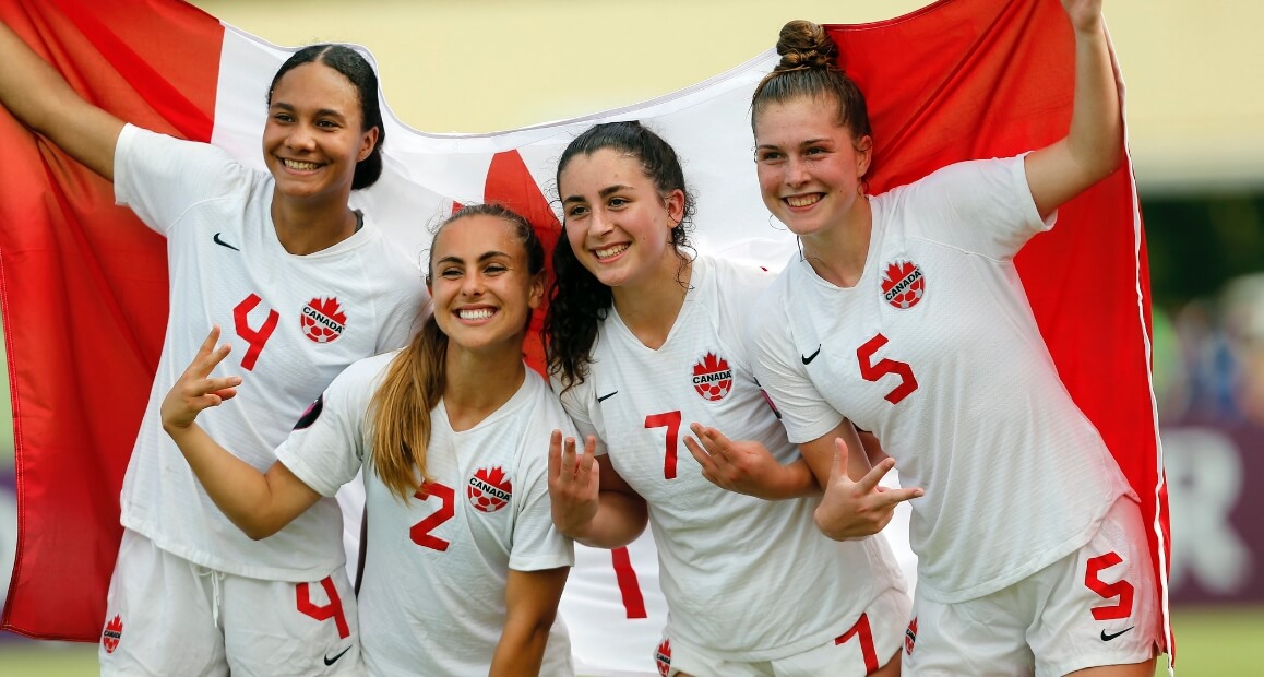 Soccer players holding Canada flag